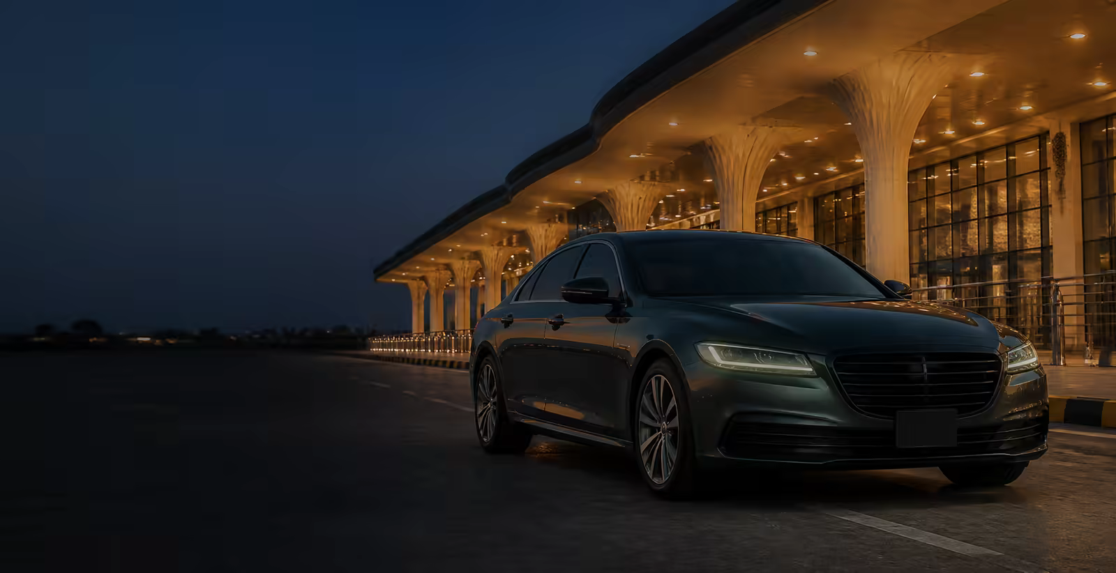 Unbranded chauffeur car outside a modern airport terminal at dusk
